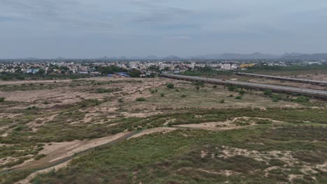 Aerial-drone-shot-of-dried-river-with-bridge-passing-through-the-city