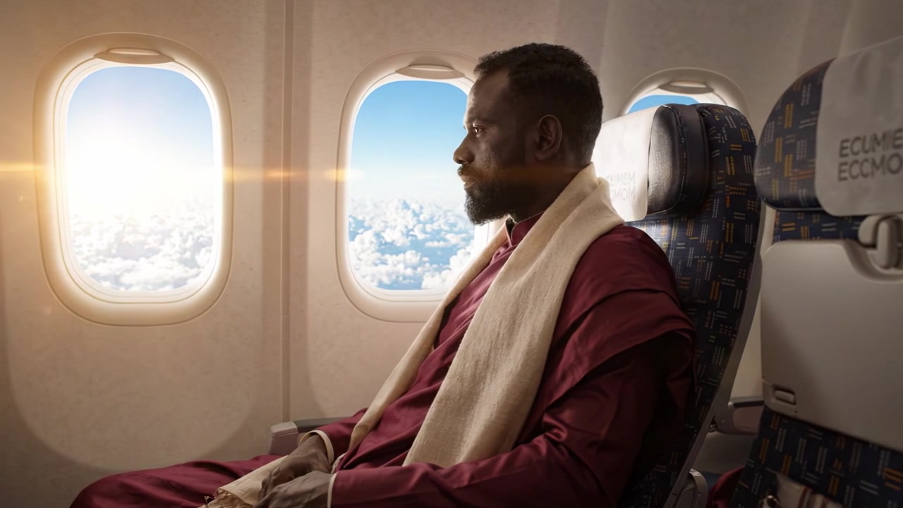 Un viaggiatore contemplativo guarda fuori dal finestrino dell'aereo, riflettendo sulla vita e sul viaggio che lo attende, circondato dalle nuvole sotto un bellissimo sorgere del sole