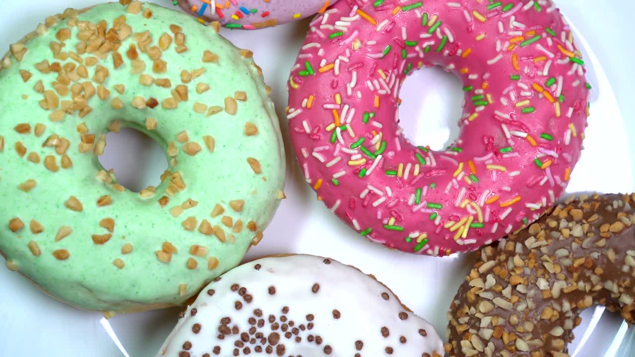 muchas rosquillas brillantes y coloridas rosquillas, tiro macro, girando lentamente en una placa giratoria