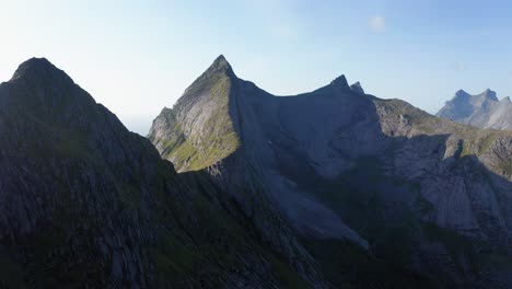 drone shot of lofoten steep cliffs and mountains rising from deep blue sea