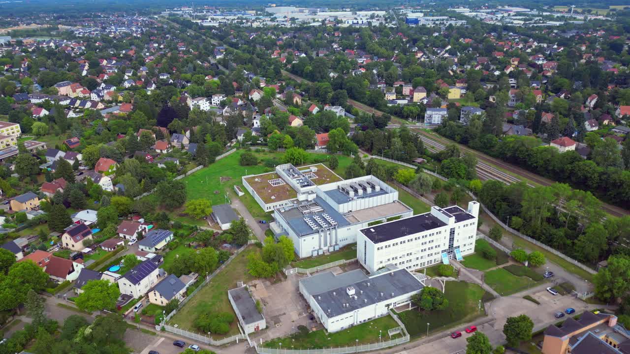 digital currency datacenter building with cooling system on the roof, surrounded by residential houses, showcasing urban and industrial integration. Magic aerial view flight circle drone footage