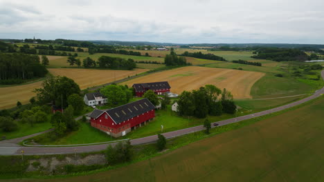 aerial over country road and red barns on farm in norwegian countryside