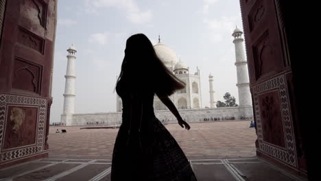 woman in dress spinning on herself with taj mahal in the background