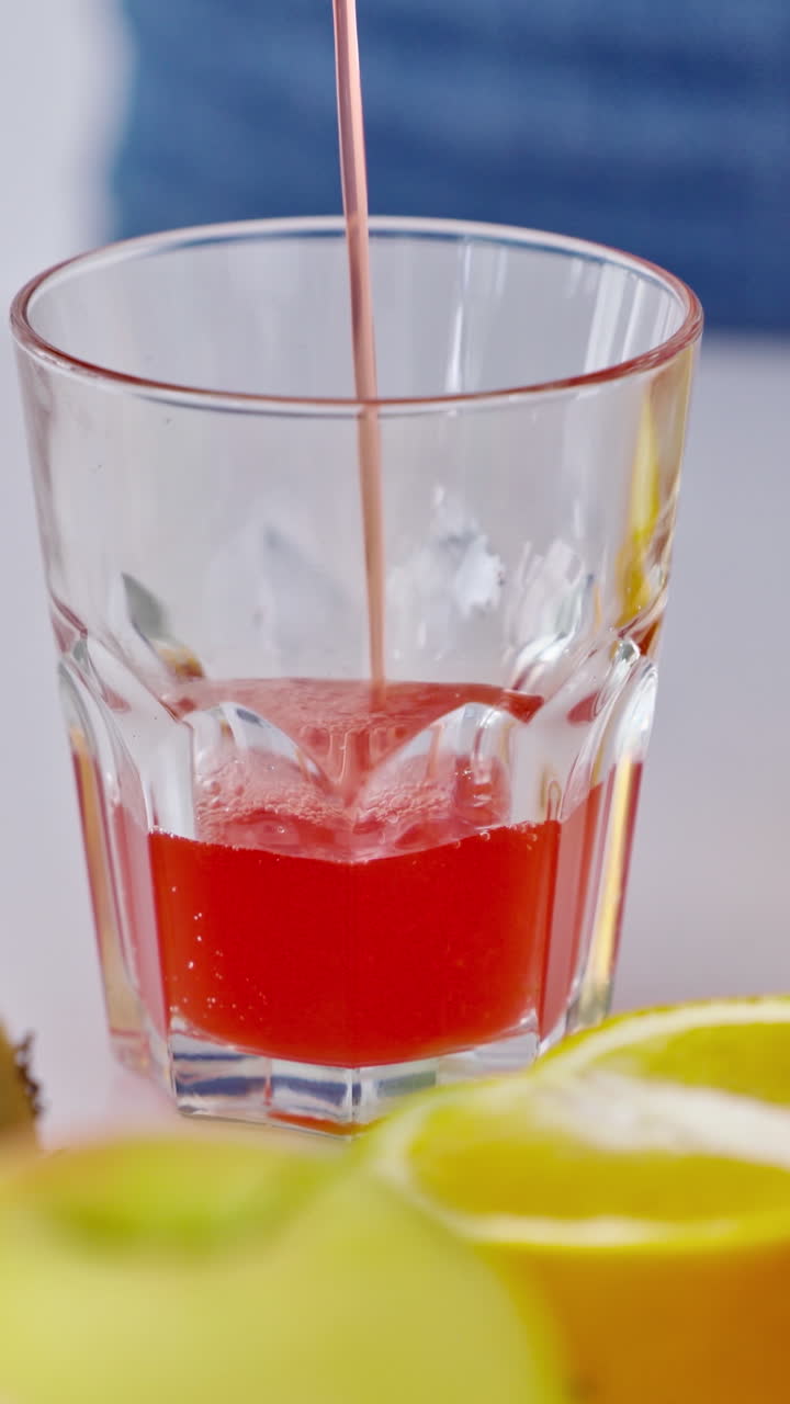 Woman preparing juice in the kitchen. Close up of woman preparing healthy fruit juice. Vertical video