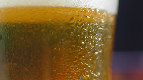 beer closeup. pint of cold craft beer isolated on matte black background rotation 360 degrees. glass of beer with water drops.