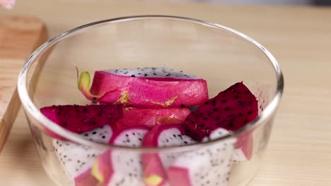 hands arranging dragon fruit in a bowl