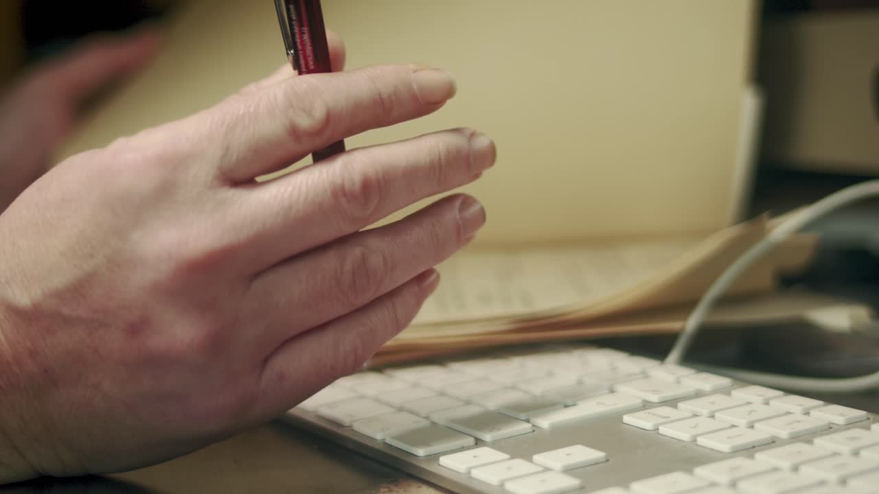 Close up of hands holding a pen and reviewing a document at a desk