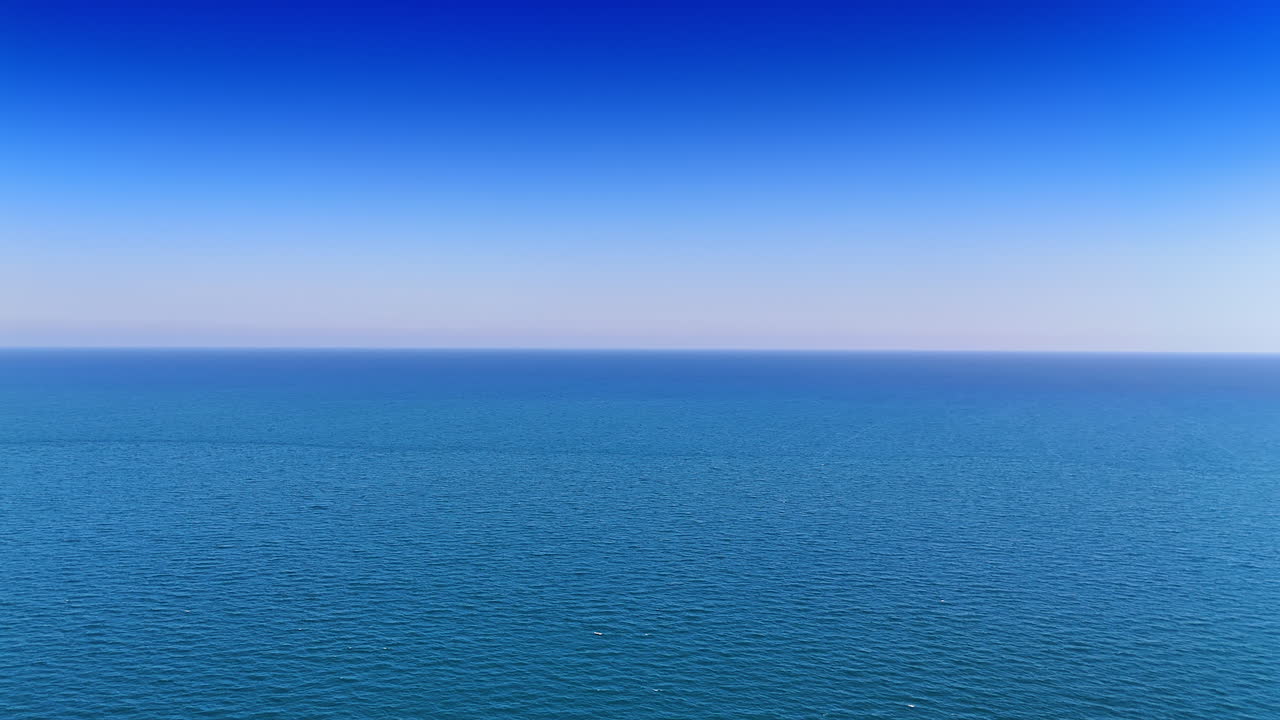 Vast ocean view under clear blue sky. The ocean stretches endlessly under a bright blue sky, showcasing tranquil waves and serenity
