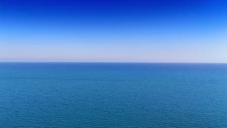 Vast ocean view under clear blue sky. The ocean stretches endlessly under a bright blue sky, showcasing tranquil waves and serenity