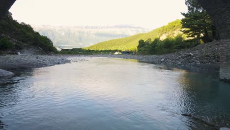 Vista-Aérea-Que-Pasa-Por-El-Interior-Del-Antiguo-Puente-De-Piedra-En-Forma-De-Arco-Y-Los-Baños-Termales-De-Benja-En-Permet,-Albania