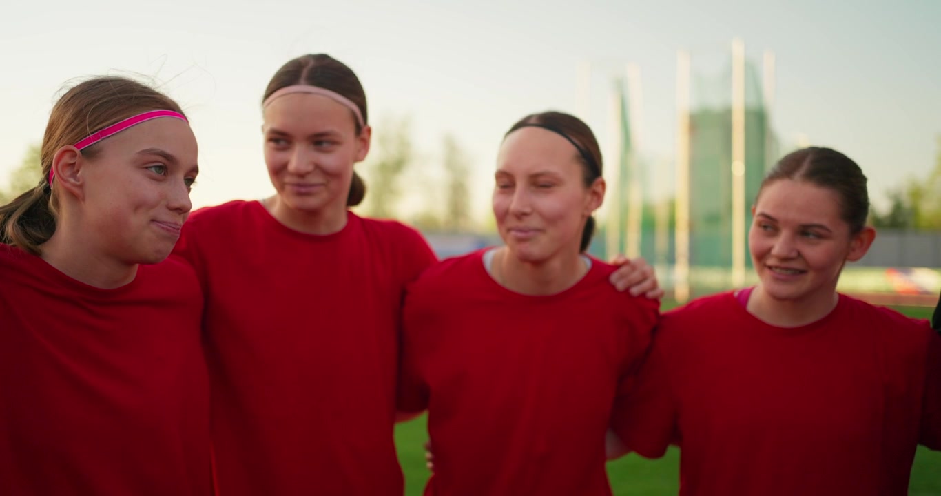 Joven equipo de fútbol femenino feliz haciendo una piña en un campo deportivo
