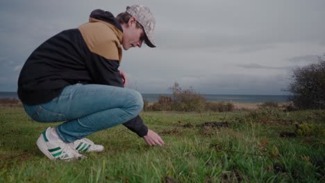 young and tall biologist finds a mushroom in vårhallarna, simrishamn, sweden and throws it away - tracking medium shot to wide shot