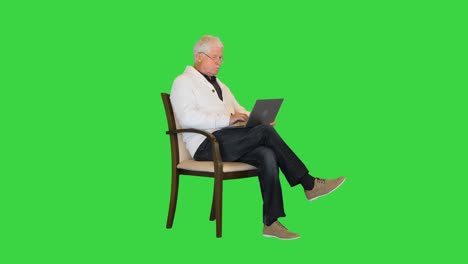 hombre viejo sentado en un sillón usando una computadora portátil en una pantalla verde, clave de croma