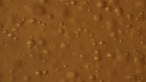 Hundreds-of-little-bubbles-floating-in-orange-liquid-substance,-MACRO