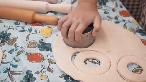 children hands cutting round pieces from rolled dough for baking cookies in culinary school. young cook preparing dough for pastry in bakery master class. cooking lesson in school.