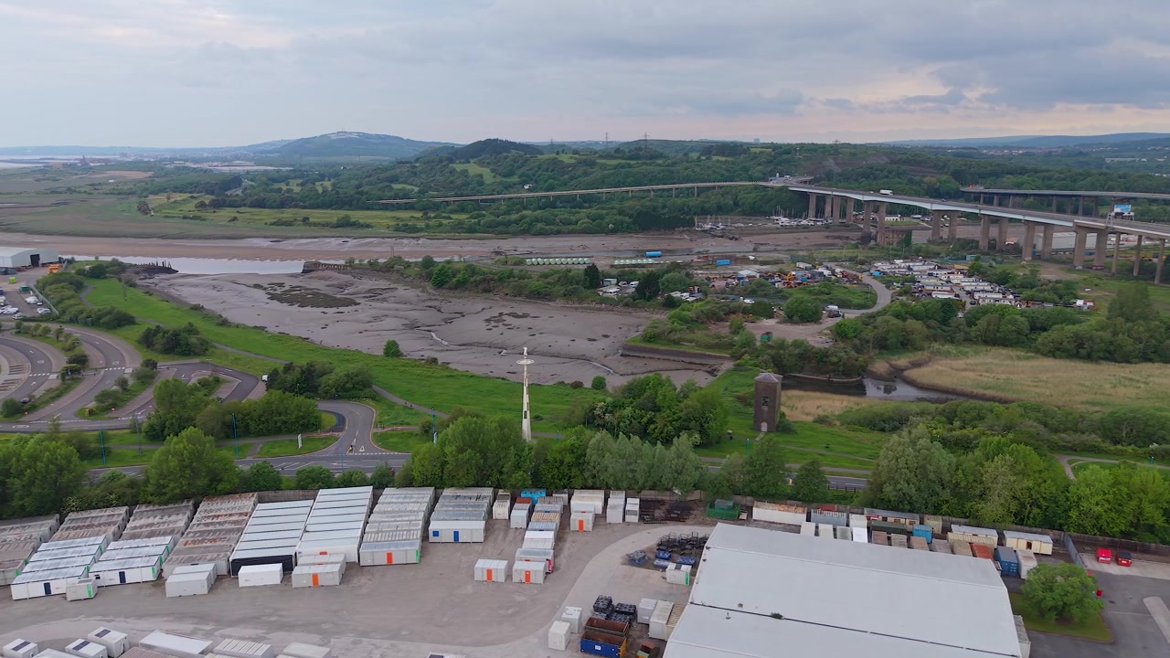 Aerial View of River Neath with M4 Motorway Overpass with Industrial Hub with Shipping Containers at Low Tide.