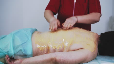 therapist does honey massage of patient back in clinic