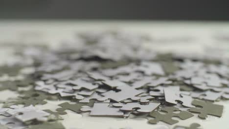 water drops falling on a white and gray puzzle pieces laying randomly on a white surface. shot in 4k;  shallow depth of field.