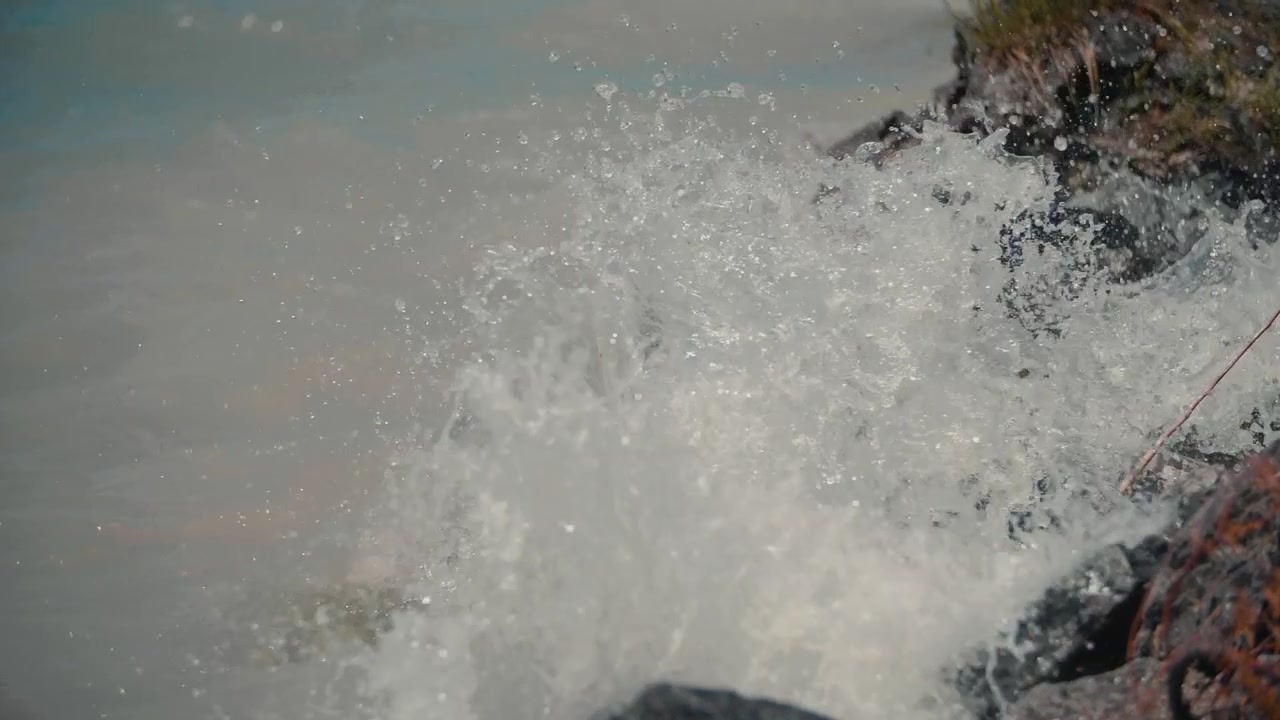 Slow Motion Water Splashing Against Rocks on a Sunny Shore