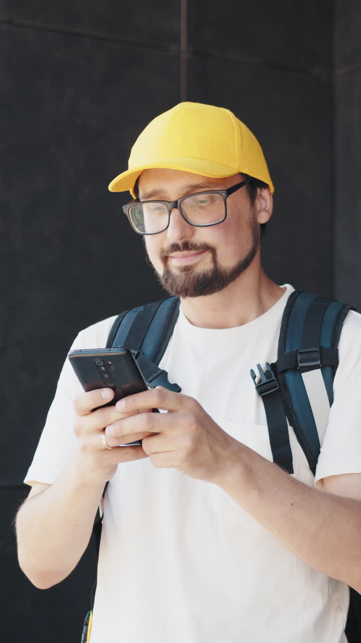 Man in yellow cap using smartphone outdoors