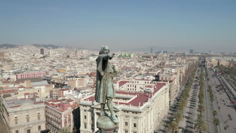 Orbit-shot-around-Columbus-Monument.-Statue-on-column-high-above-streets.-Buildings-in-city-in-background.-Barcelona,-Spain