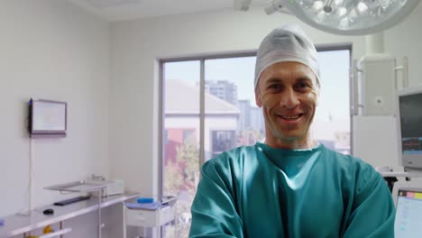 retrato de un cirujano de pie con los brazos cruzados en la sala de operaciones