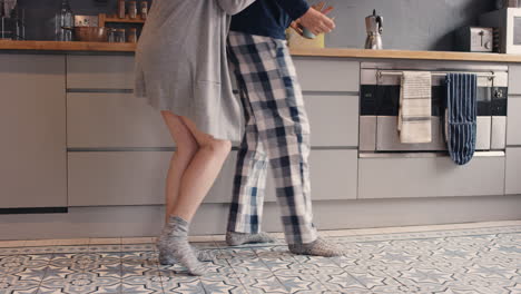 happy young couple newly wed dancing listening to music in kitchen wearing pajamas morning at home in love