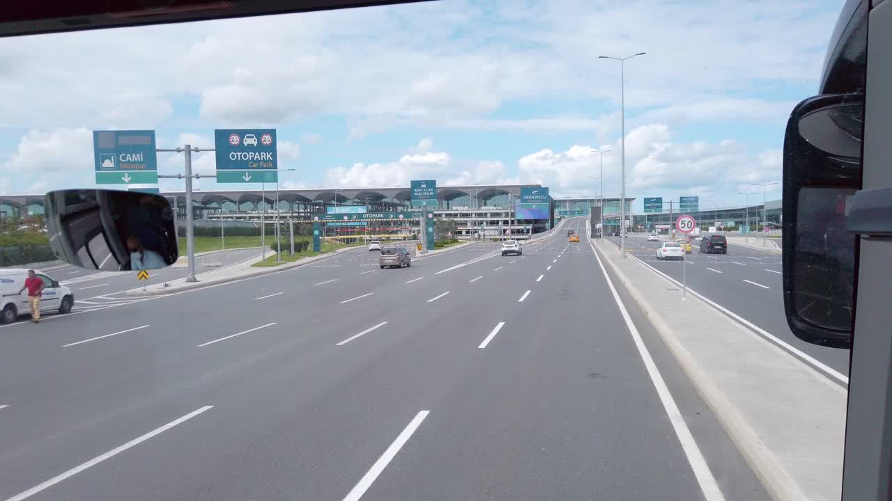 On a partly cloudy day, a shot from a bus approaching Istanbul Airport's terminal