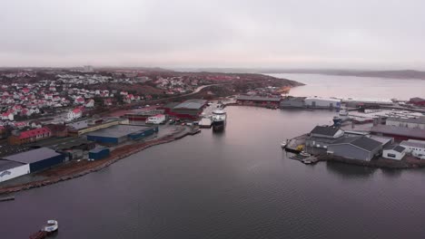 The-beautiful-Lysekil,-Sweden-with-a-small-shipping-vessel-docked,-preparing-for-leaving---Aerial-shot