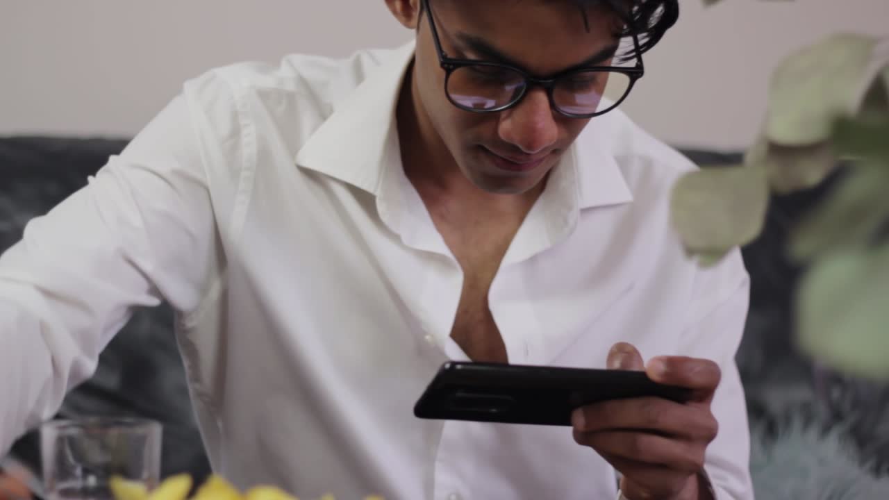 estilo de vida no saludable, joven juega juegos en el teléfono y come papas fritas en el sofá