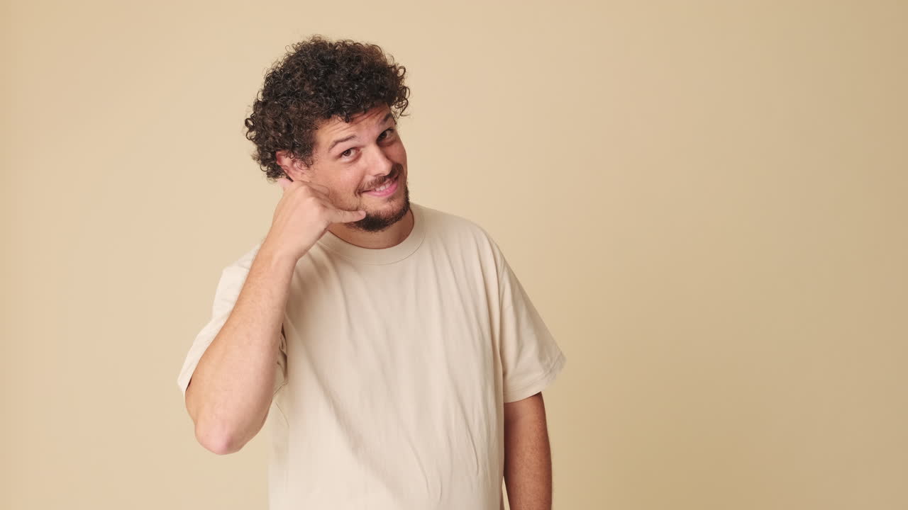 Smiling Man with Curly Hair Making Call Me Gesture