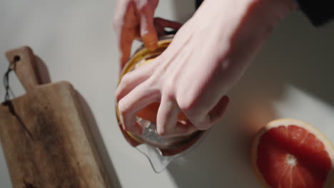 presionar jugo de pomelo en un exprimidor de jugo en la cocina para un cóctel