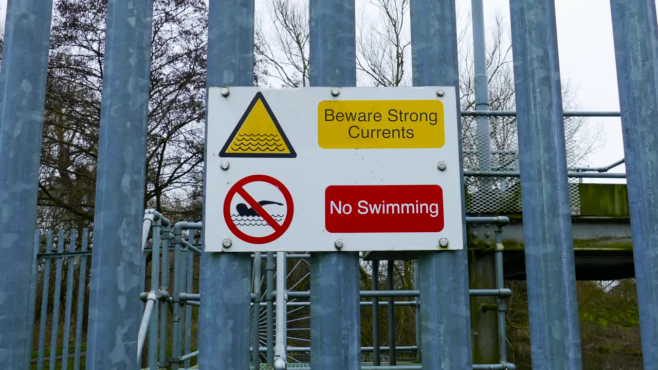 остерегайтесь сильного течения и знака "не купаться" на стене из металлических прутьев с барьером