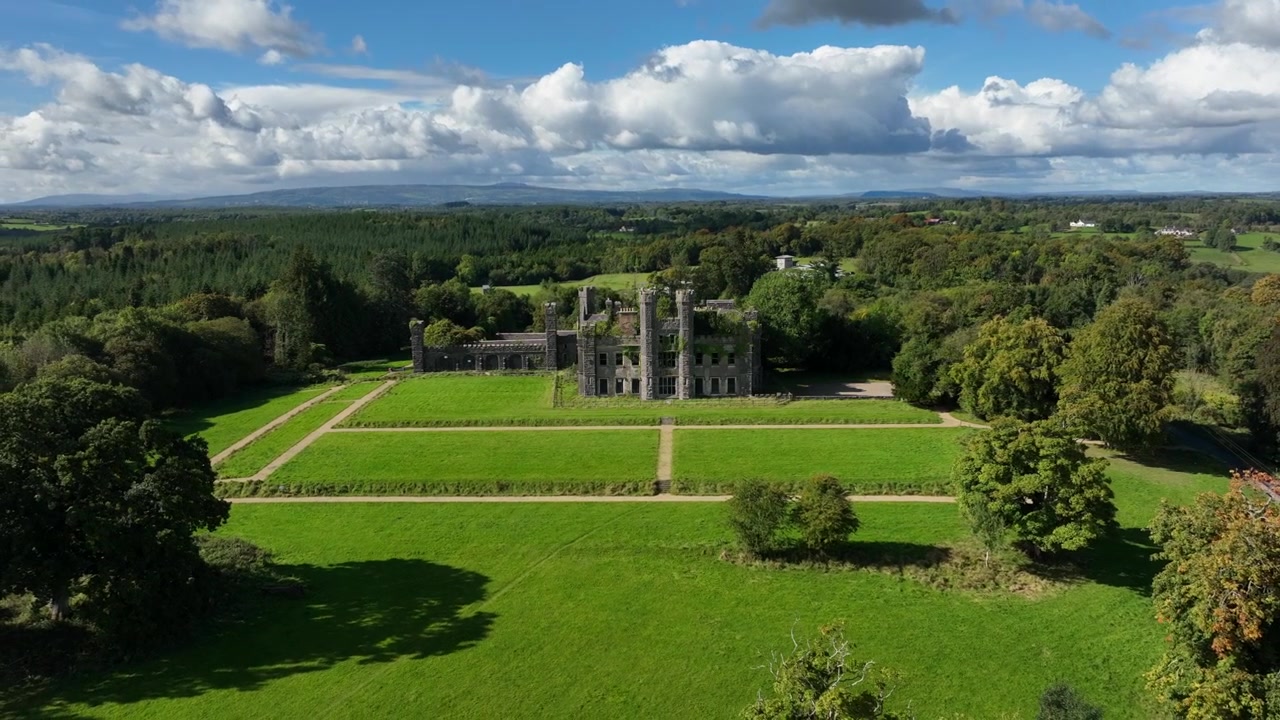 Castello Saunderson, Contea di Cavan, Irlanda, settembre 2022. Il drone orbita in senso antiorario mentre si allontana per rivelare il vecchio castello in rovina in stile neogotico circondato da prati e un paesaggio suggestivo.