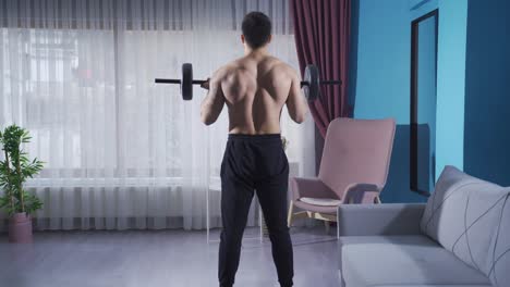 young man doing barbell curls. athlete young man trains at home.