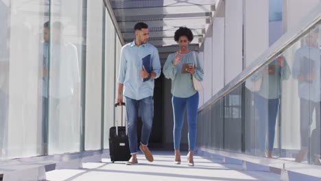 video of diverse businessman and businesswoman walking with suitcase and talking