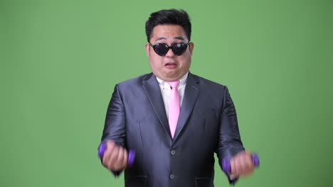 초록색 배경에 젊은 잘생긴 과체중 아시아 사업가
