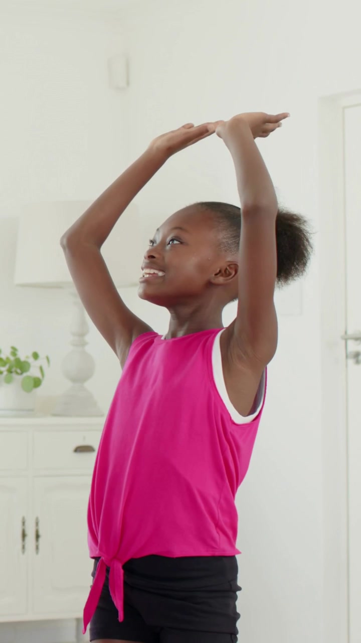 Vertical video: Starting girl in pink top warming near cabinet at home, reaching to clap with adult