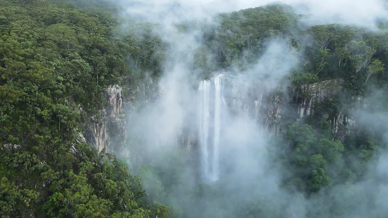 la montaña cubierta de niebla revela una majestuosa cascada tropical que cae en cascada por un acantilado.