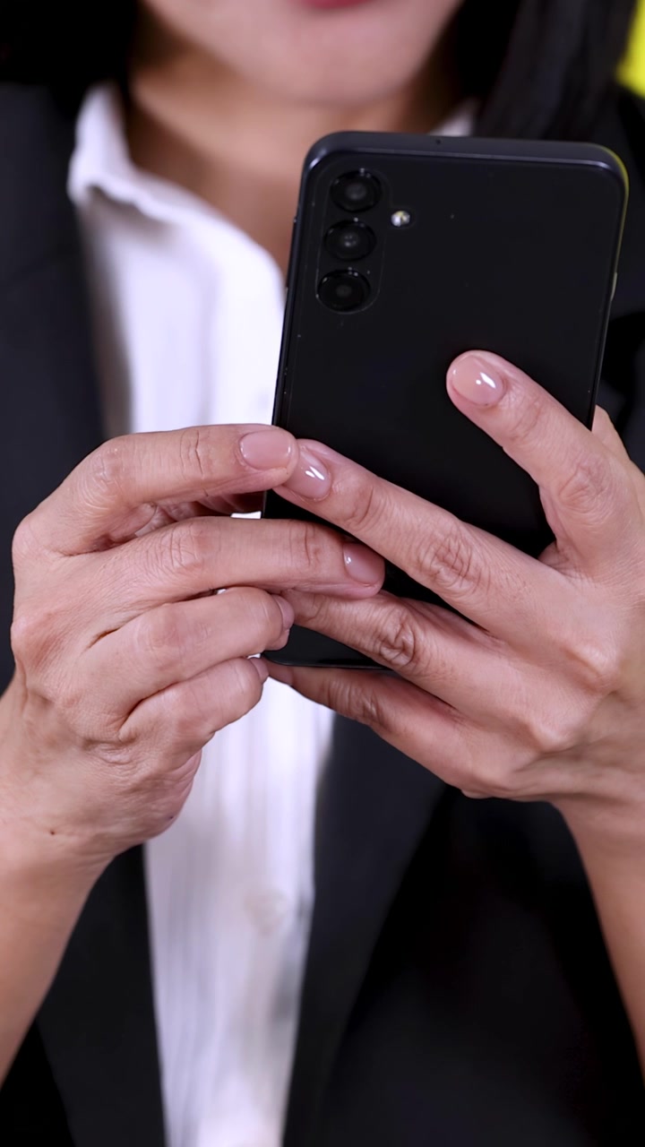 Primo piano delle mani di una donna d'affari che digitano su uno smartphone, inquadratura verticale, telecamera fissa, illuminazione brillante da studio.