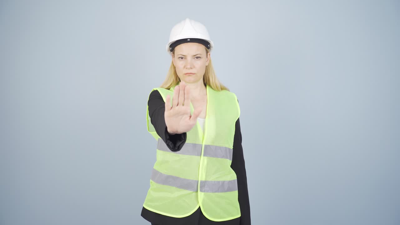 el ingeniero mira a la cámara y hace una señal de alto.