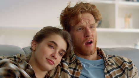 young couple watching boring film at home closeup. sleepy family hugging on sofa