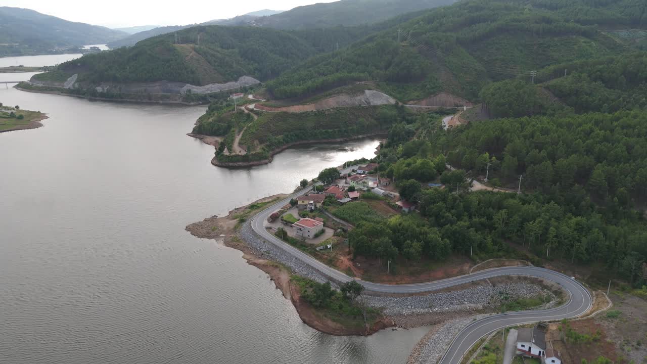 aérea - río támega que limita con una montaña en ribeira de pena, portugal, con carreteras sinuosas y casas a lo largo de la costa