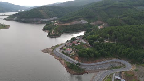 aerial - tâmega river bordering a mountain at ribeira de pena, portugal, with winding roads and houses along the shoreline