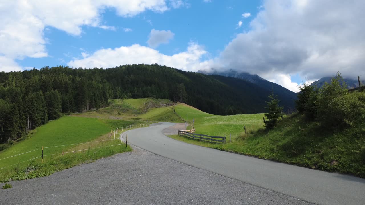 A nostalgic drive through the Austrian Alps: this aerial clip captures a 1960s Pontiac cruising a narrow mountain valley road, surrounded by lush green slopes and serene nature