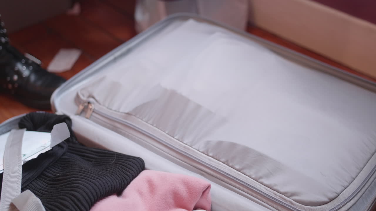 여행 가방을 포장한 다음 지퍼를 닫으려고 손을 닫고 어려움을 겪습니다.