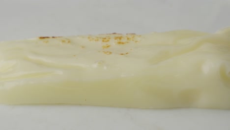 primer plano de queso mozzarella en fusión con manchas de quemaduras sobre un fondo blanco