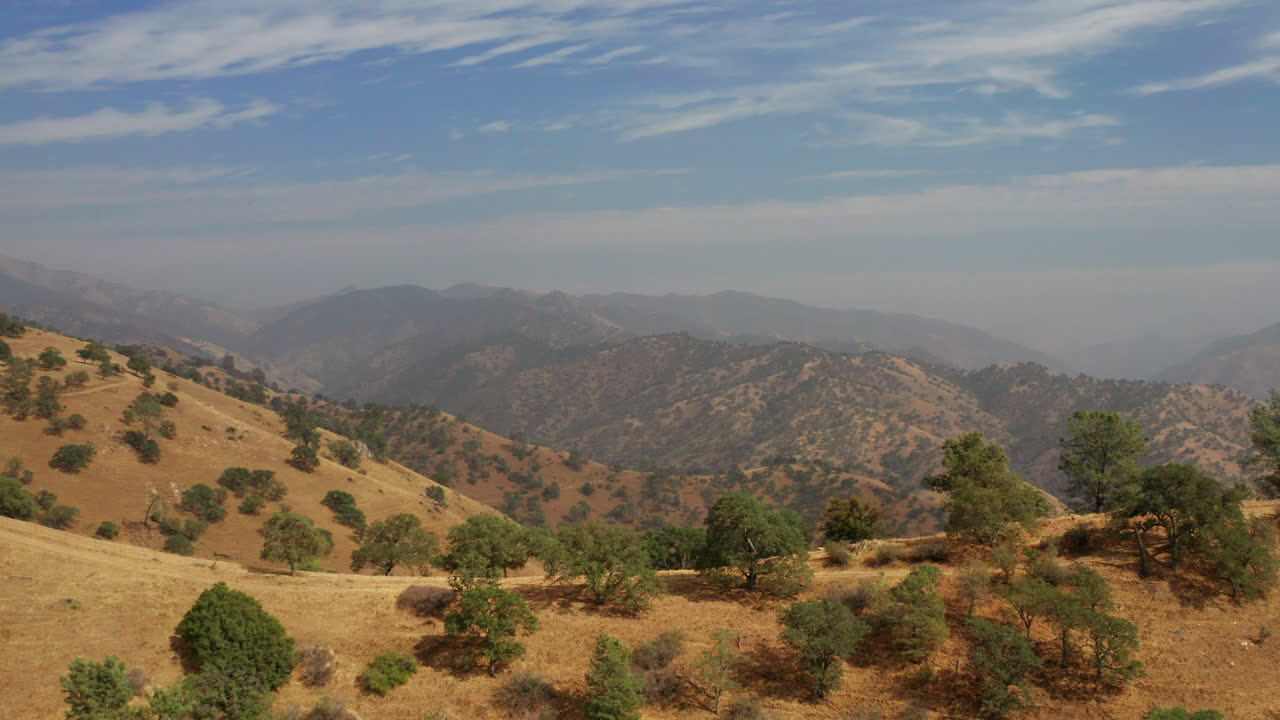 Vista aerea con panning della catena montuosa del Deserto Rosso nell'alto deserto della California meridionale, avvolta da una foschia fumosa dovuta agli incendi