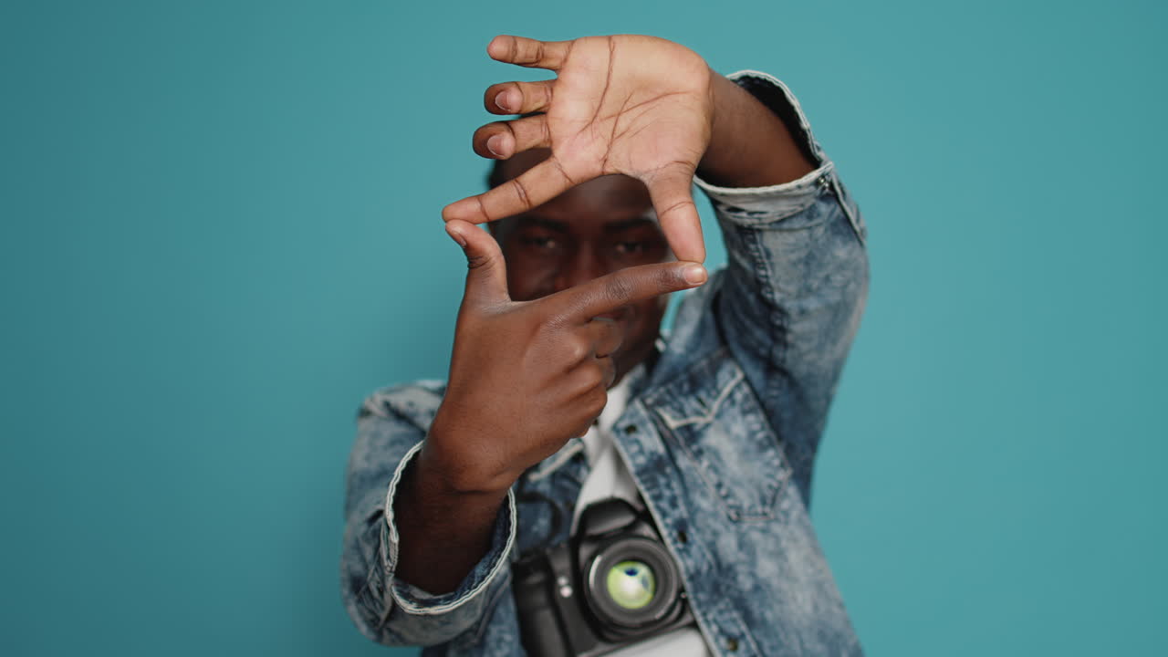 Male model doing frame shape sign with hands in front of studio camera