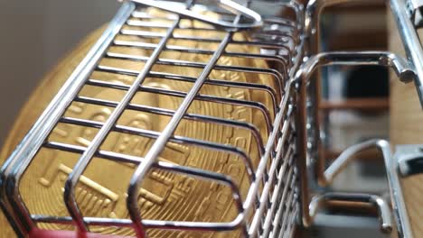 Vertical-clip:-Gold-bitcoin-crypto-currency-in-tiny-shopping-cart-on-kitchen-table-concept-low-angle-close-up-reverse-shot